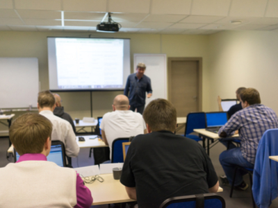 A business workshop where an instructor is talking in front of a screen projector