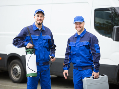 Two pest control workers in uniform and carrying equipment